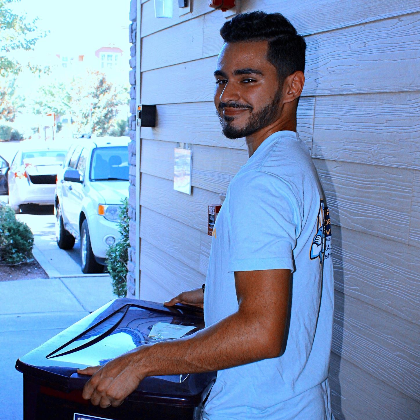 YBM crew member smiling at the camera and carrying box